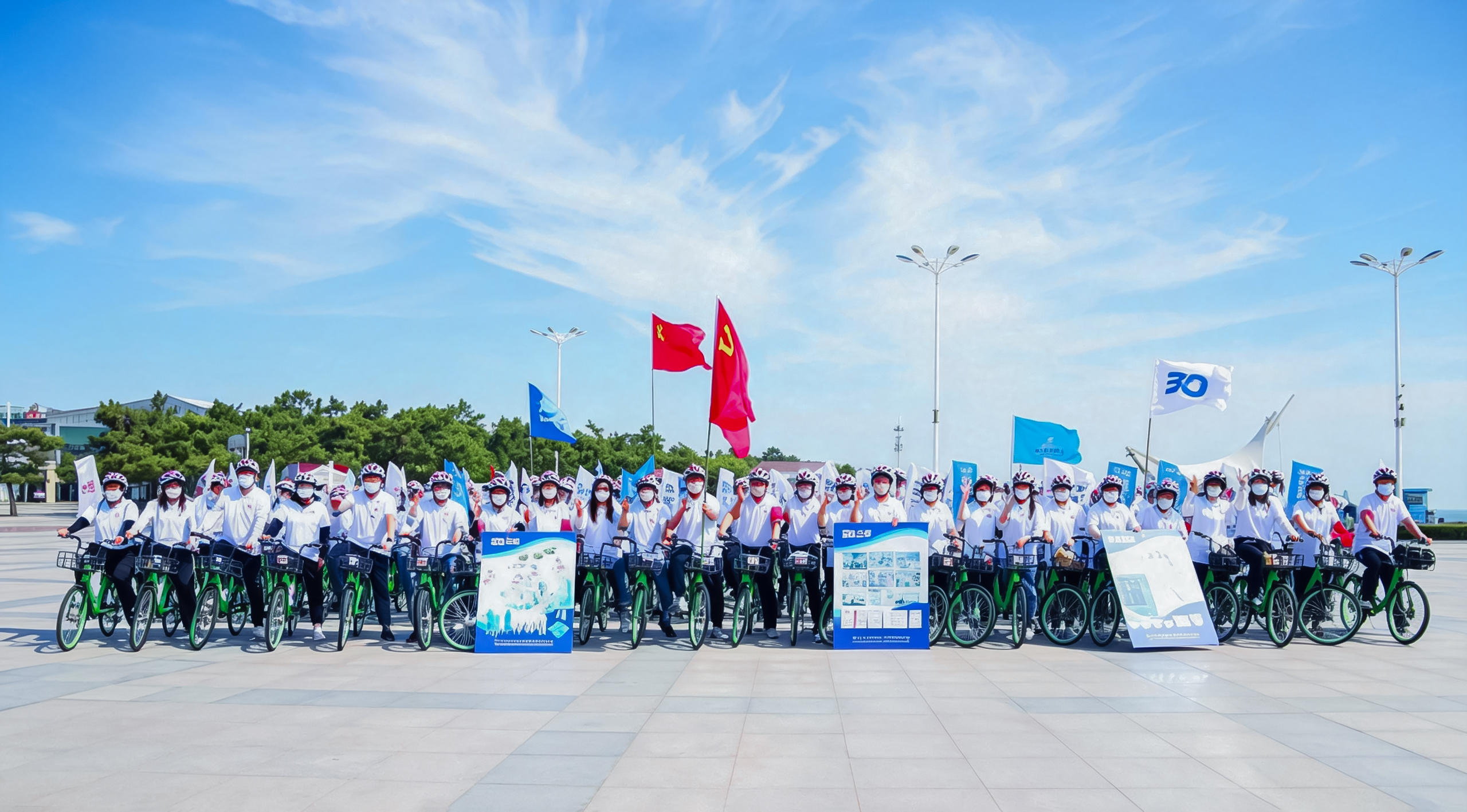 A large group of Sanqi employees gathered with bicycles and company flags